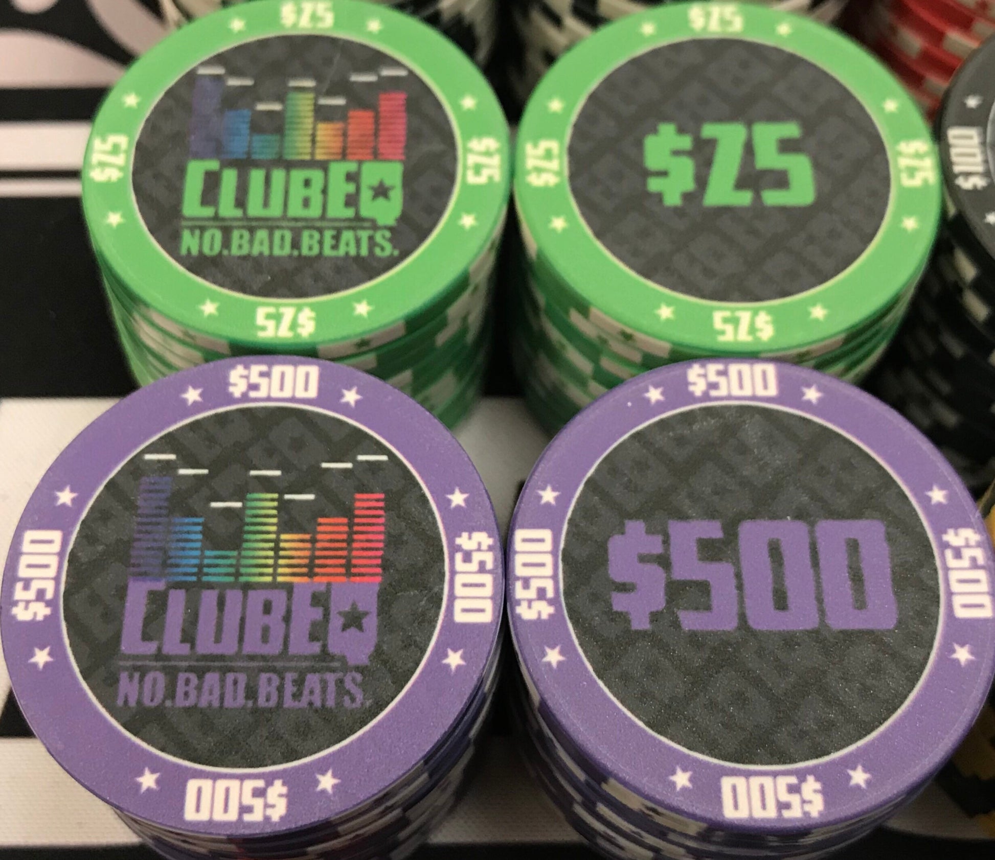 Here we see the twenty-five dollar ($25) and five-hundred dollar ($500) ClubEQ poker chips in lime green and purple, respectively. The ClubEQ logo resembles a lighted EQ band. On the other side of each chip is the denomination in the same color as the poker chip.