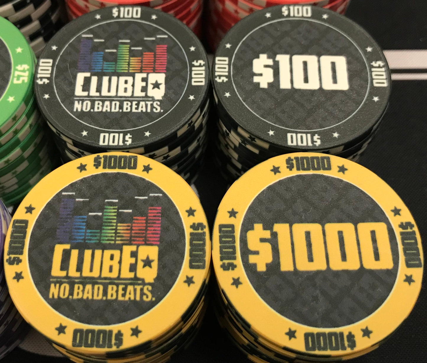 Here we see the one hundred dollar ($100) and one thousand dollar ($1000) ClubEQ poker chips in black and yellow, respectively. The ClubEQ logo resembles a lighted EQ band. On the other side of each chip is the denomination in the same color as the poker chip.