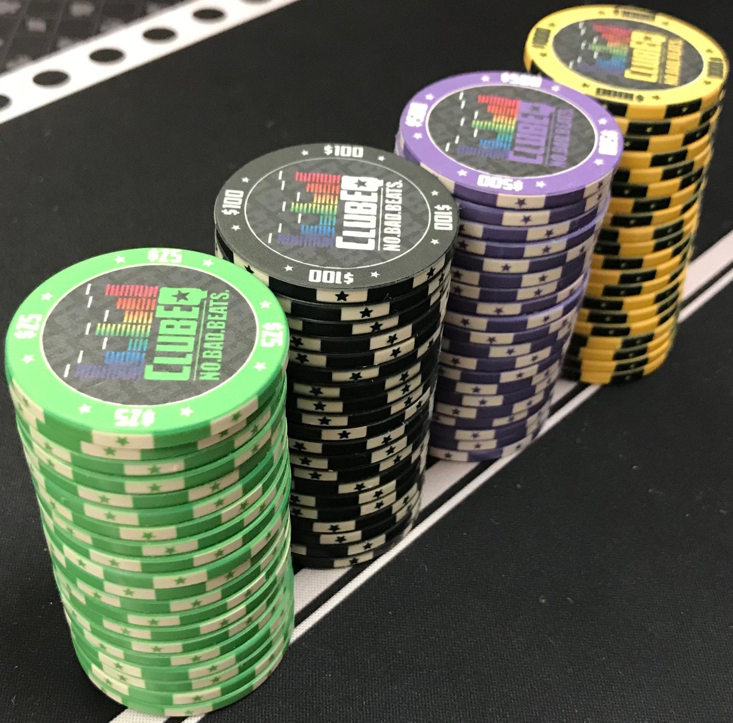 Four stacks of 20 ClubEQ designer poker chips. The ClubEQ green $25, black $100, purple $500, and yellow $1000 poker chips. (Green, black, purple, yellow.) If you're looking for unique poker chips, these are the answer.