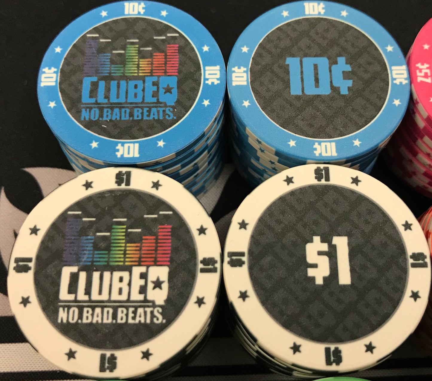 Here we see the ten cent (10¢) and one dollar ($1) ClubEQ poker chips in light blue and white, respectively. The ClubEQ logo resembles a lighted EQ band. On the other side of each chip is the denomination in the same color as the poker chip.